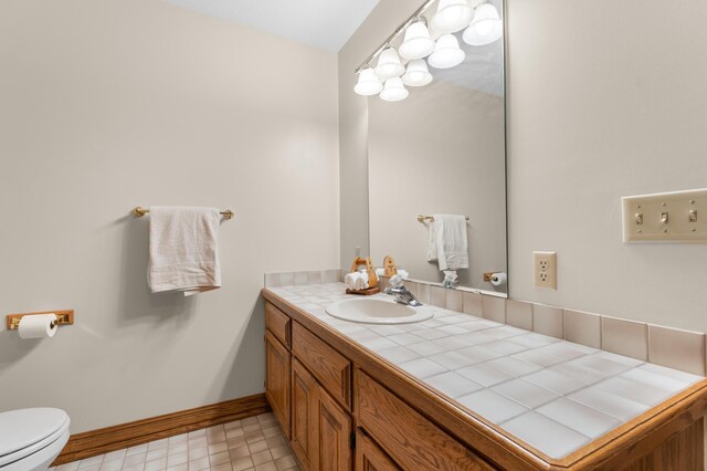 bathroom featuring vanity, toilet, and baseboards