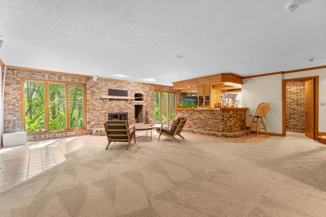 living area with brick wall, a textured ceiling, carpet floors, a brick fireplace, and ornamental molding