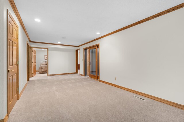 empty room with crown molding, light colored carpet, baseboards, and recessed lighting