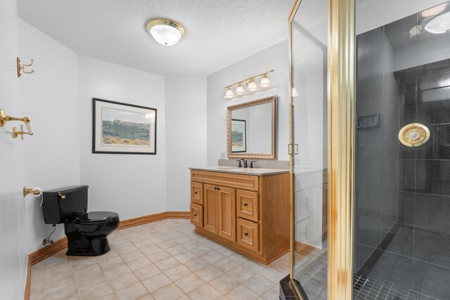 full bath featuring toilet, a tile shower, vanity, a textured ceiling, and baseboards