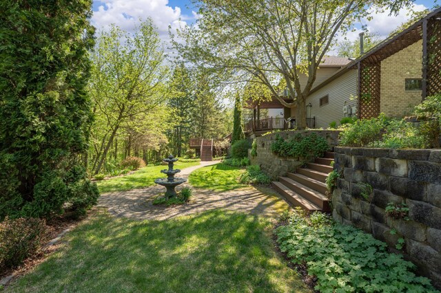 view of grassy yard featuring stairs and a wooden deck
