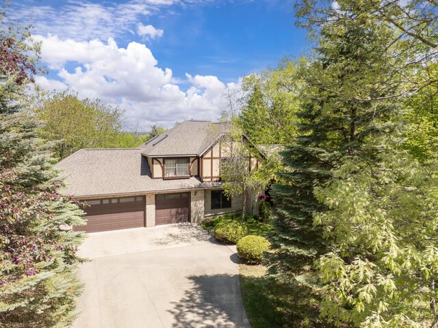 view of front of property with concrete driveway, a shingled roof, and a garage