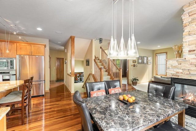 dining area featuring recessed lighting, wood finished floors, a fireplace, and stairs