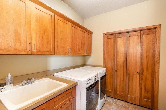 washroom with a sink, independent washer and dryer, light tile patterned floors, and cabinet space