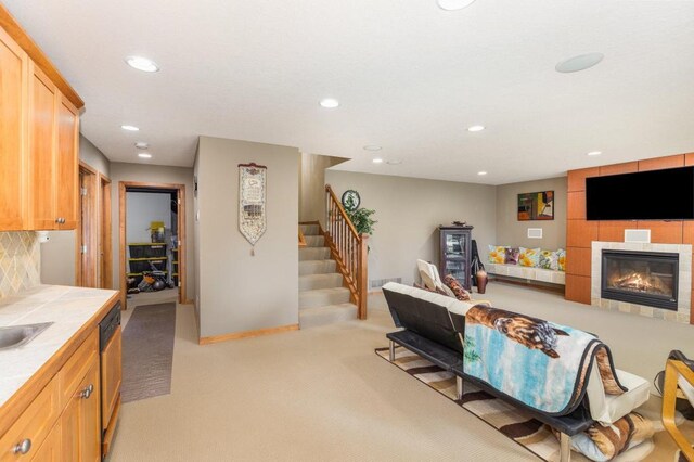 living area featuring stairs, a fireplace, light colored carpet, baseboards, and recessed lighting