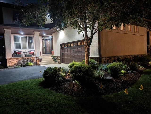 view of front of home with a garage, stucco siding, stone siding, and concrete driveway