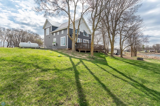 back of house with a lawn, a standing seam roof, a deck, and metal roof