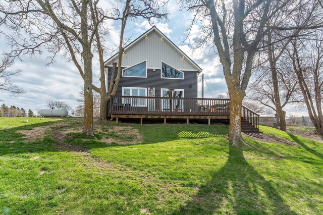 rear view of property featuring board and batten siding, a wooden deck, and a yard