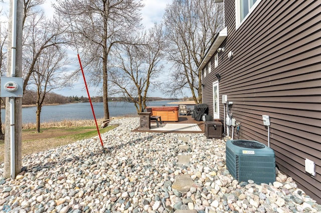view of yard featuring a hot tub, a water view, central AC, and a patio area