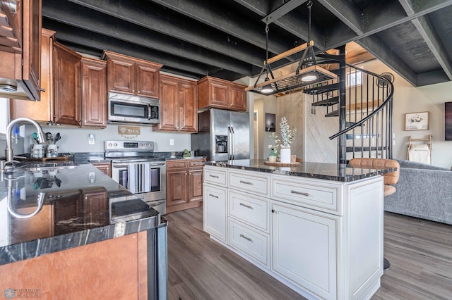 kitchen featuring dark stone counters, stainless steel appliances, a sink, and wood finished floors