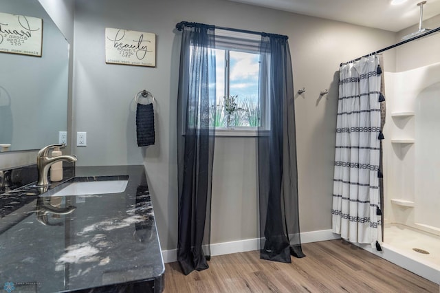 bathroom featuring vanity, baseboards, wood finished floors, and a stall shower
