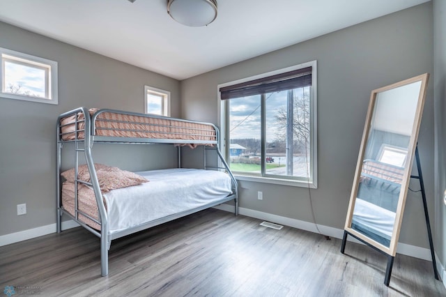 bedroom with baseboards, wood finished floors, and visible vents
