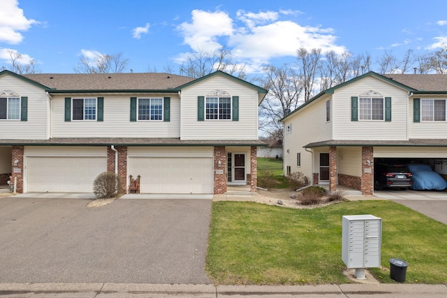 view of front of house with driveway, a front yard, brick siding, and a garage