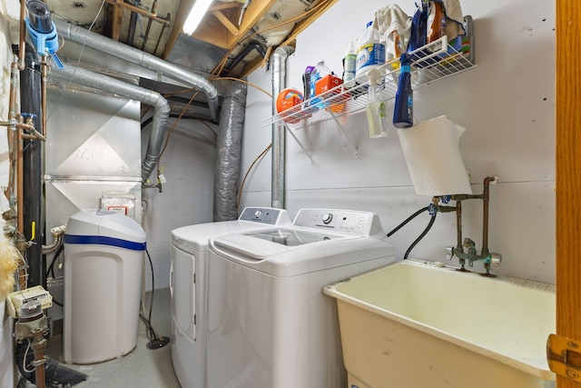clothes washing area featuring separate washer and dryer, laundry area, and a sink