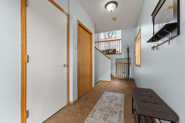 hallway with tile patterned flooring, stairs, and a textured ceiling