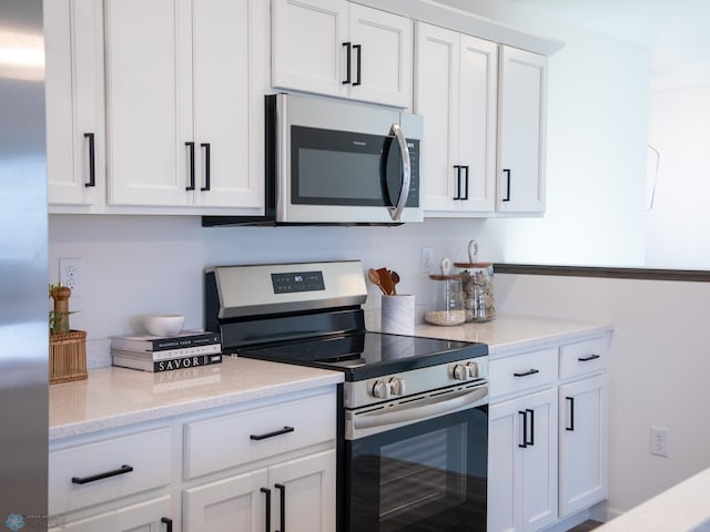 kitchen with appliances with stainless steel finishes, white cabinets, and light stone counters
