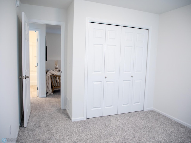 unfurnished bedroom featuring carpet floors, baseboards, and a closet