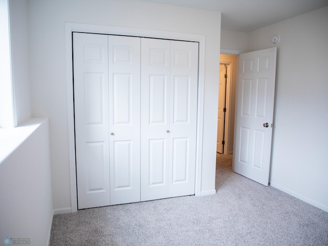 unfurnished bedroom featuring carpet floors, baseboards, and a closet