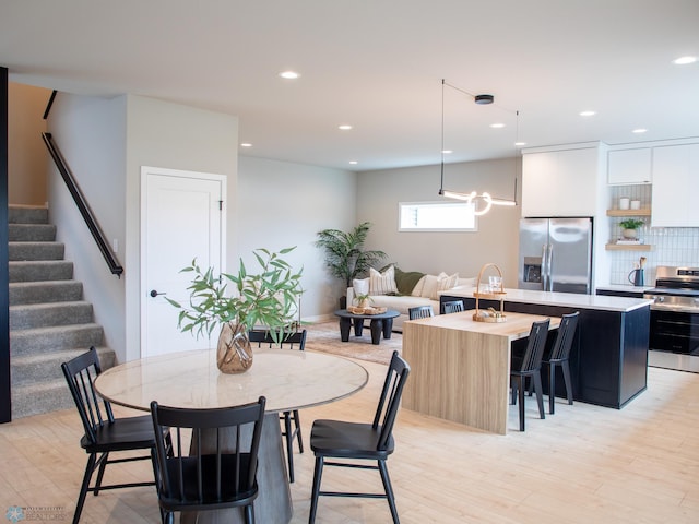 dining area featuring recessed lighting, light wood finished floors, and stairs