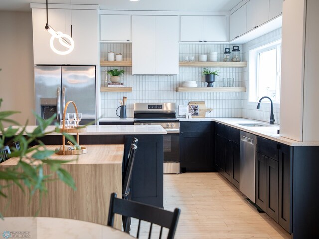 kitchen featuring decorative backsplash, appliances with stainless steel finishes, open shelves, a sink, and light countertops