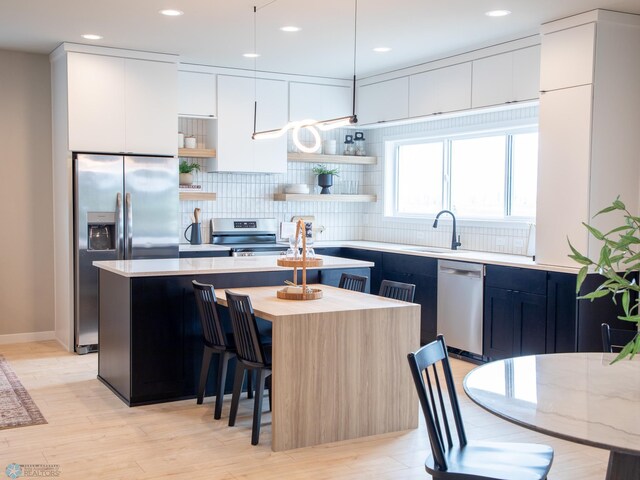 kitchen with decorative backsplash, a kitchen island, open shelves, a breakfast bar, and stainless steel appliances
