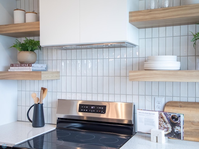 room details featuring open shelves, decorative backsplash, white cabinets, and stainless steel range with electric cooktop