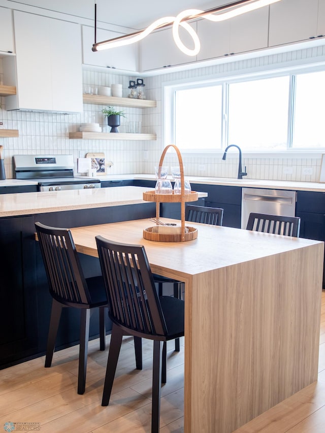 kitchen featuring open shelves, dishwashing machine, stainless steel electric stove, and a healthy amount of sunlight