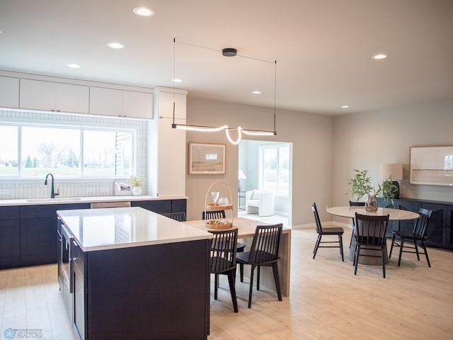 kitchen featuring a sink, light countertops, recessed lighting, light wood-type flooring, and a kitchen island