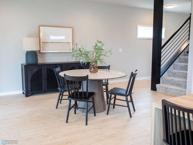 dining area featuring baseboards, light wood-style flooring, and stairs