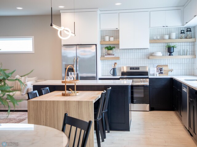 kitchen featuring appliances with stainless steel finishes, tasteful backsplash, open shelves, white cabinetry, and light wood-style flooring