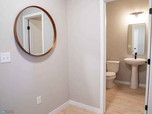 half bathroom featuring baseboards, toilet, and wood finished floors