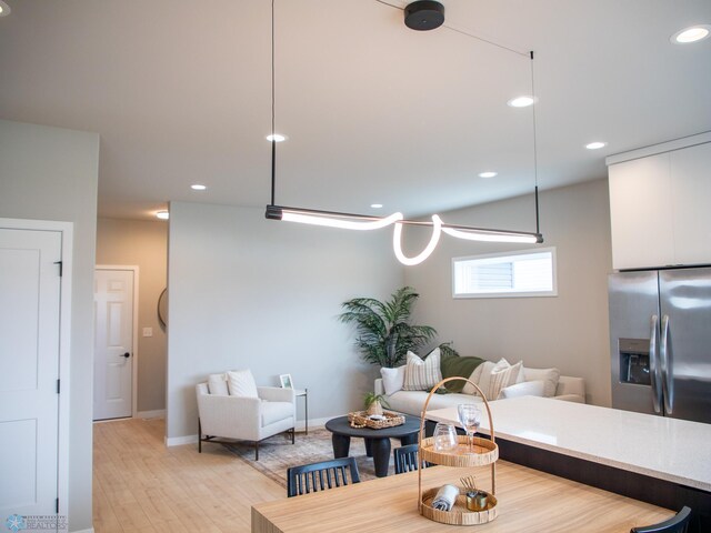 interior space with baseboards, open floor plan, recessed lighting, stainless steel fridge with ice dispenser, and light wood-style flooring