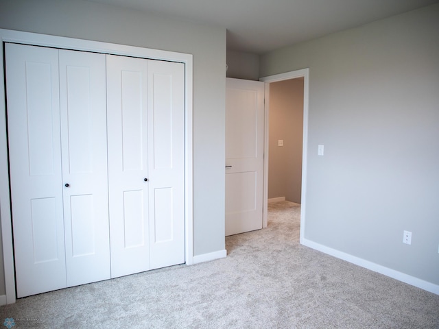 unfurnished bedroom featuring baseboards, carpet, and a closet