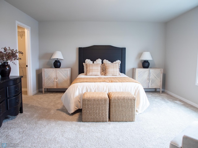 carpeted bedroom featuring baseboards and a walk in closet