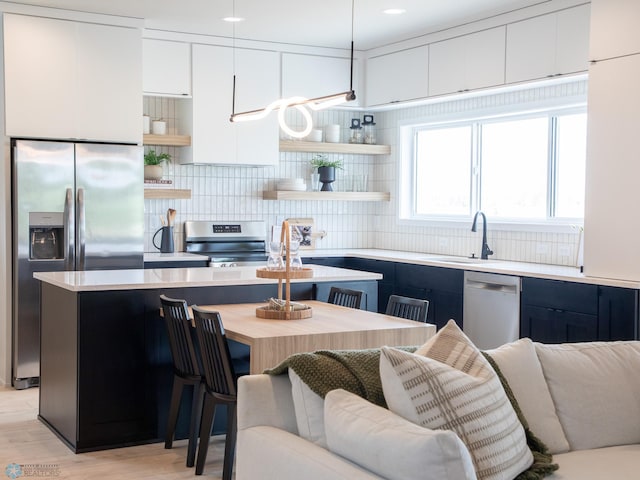 1479 66th Ave S, Fargo, ND 58104 - kitchen featuring appliances with stainless steel finishes, open shelves, a sink, light countertops, and decorative backsplash