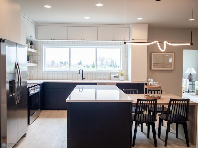 1479 66th Ave S, Fargo, ND 58104 - kitchen featuring stainless steel appliances, a sink, light countertops, light wood-type flooring, and backsplash