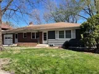 view of front of property with a chimney, a front lawn, and an attached garage