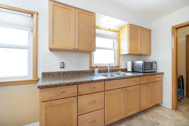 kitchen featuring dark countertops, light brown cabinetry, a sink, and stainless steel microwave