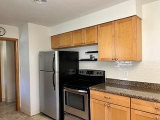 kitchen featuring tasteful backsplash, stainless steel appliances, open shelves, and dark stone counters