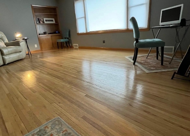 unfurnished living room with visible vents, light wood-type flooring, and baseboards