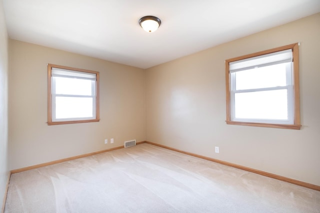 spare room featuring visible vents, light carpet, and baseboards