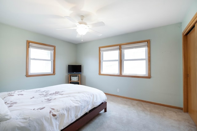 bedroom featuring a ceiling fan, baseboards, a closet, and light colored carpet