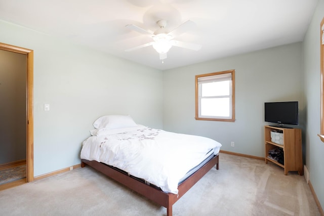 bedroom with ceiling fan, light carpet, and baseboards