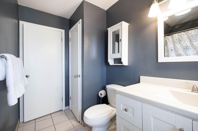 bathroom with toilet, a shower with curtain, vanity, and tile patterned floors