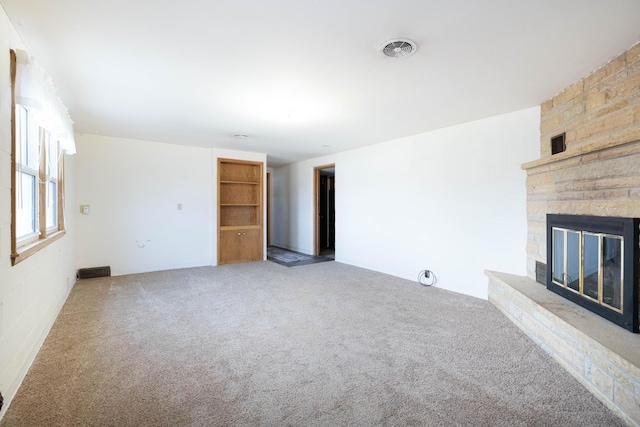 unfurnished living room with visible vents, a stone fireplace, and carpet