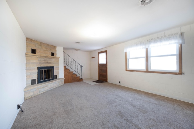 unfurnished living room with visible vents, carpet flooring, a fireplace, and stairway