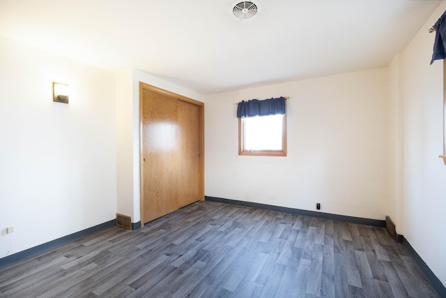 unfurnished bedroom featuring wood finished floors, a closet, visible vents, and baseboards