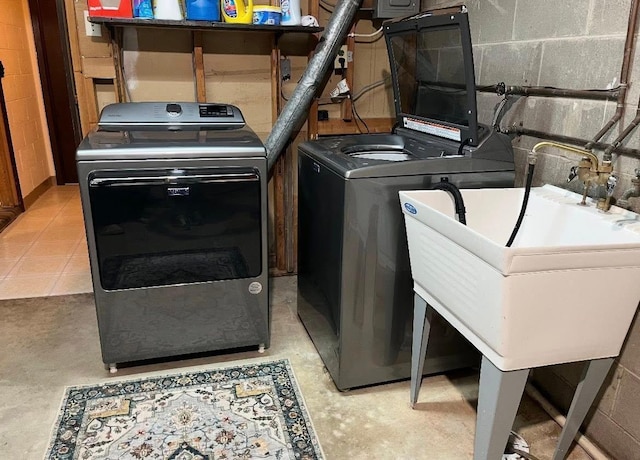 laundry room featuring washer and clothes dryer, laundry area, and concrete block wall