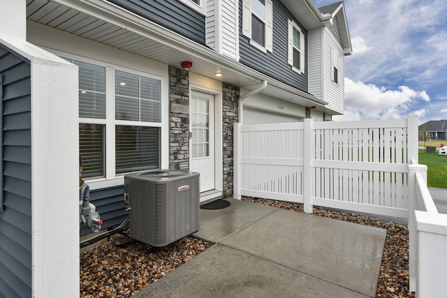 view of patio / terrace with fence, an attached garage, and cooling unit