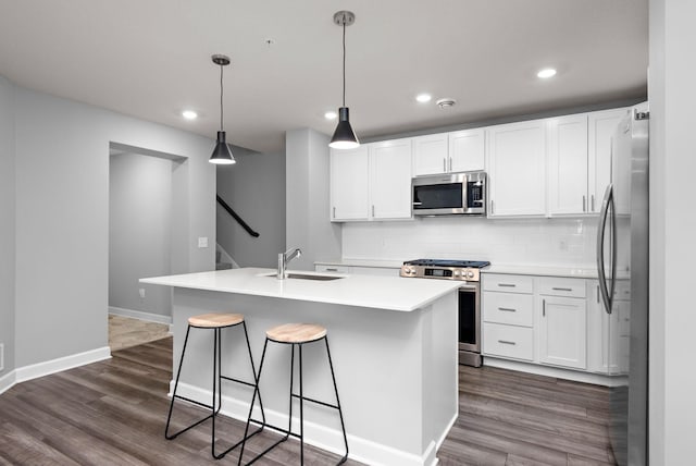 kitchen with a breakfast bar, dark wood-style floors, white cabinets, a sink, and stainless steel appliances